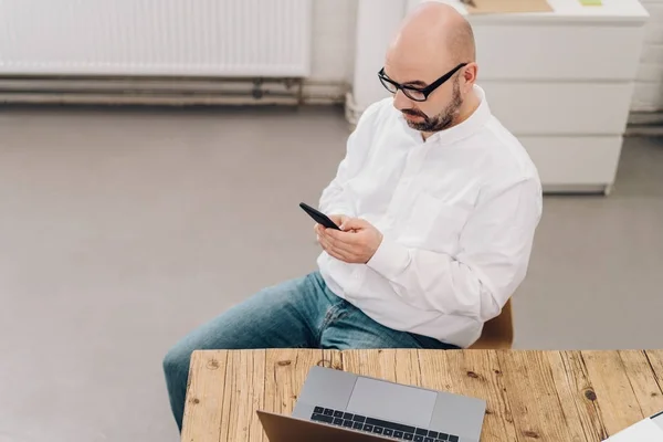 Mann benutzt Handy am Schreibtisch — Stockfoto