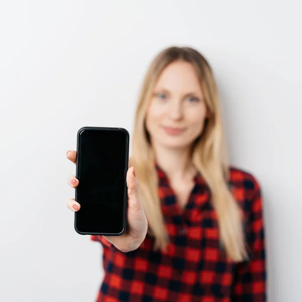 Mulher estendendo um celular em branco — Fotografia de Stock