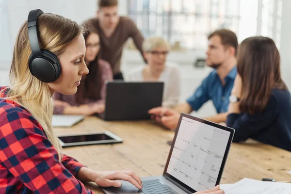 Jovem Empresária Trabalhando Usando Fones Ouvido Com Colegas Segundo Plano — Fotografia de Stock