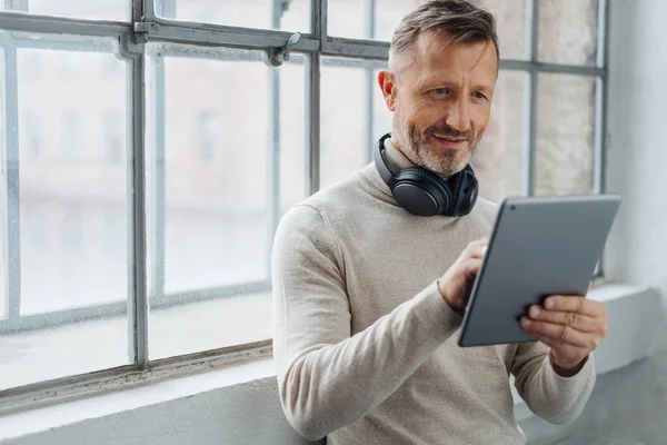 Man Met Stereohoofdtelefoon Rond Zijn Nek Browsen Een Tablet Voor — Stockfoto