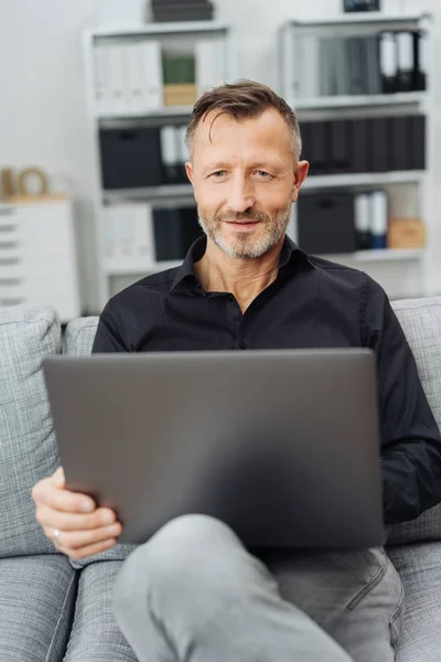 Sorrindo Homem Sentado Casa Sofá Navegando Computador Portátil Equilibrado Seu — Fotografia de Stock