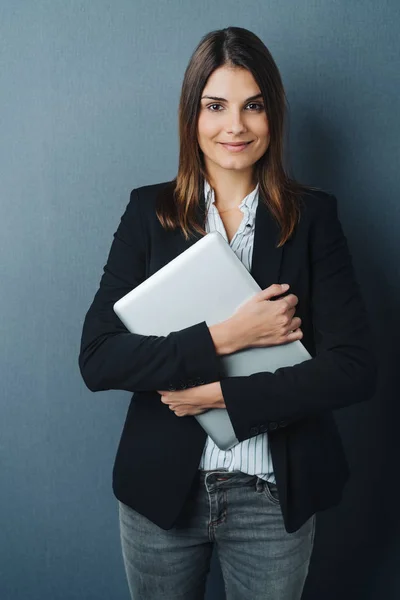 Atractiva Mujer Negocios Agarrando Portátil Pecho Mientras Sonríe Cámara Contra — Foto de Stock