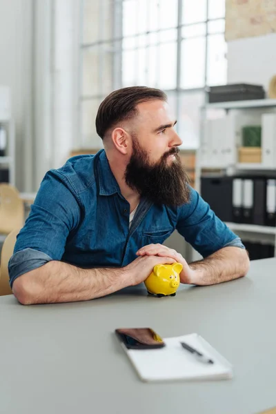 Skäggig Omtänksamma Man Sitter Vid Skrivbord Med Gula Spargris — Stockfoto