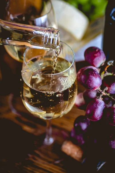 Man is pouring white wine into the glasses — Stock Photo, Image