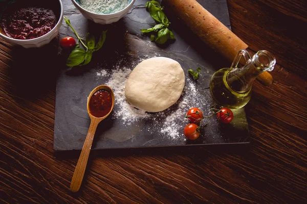 Тесто с мукой на деревянном столе, приготовление домашней пиццы — стоковое фото
