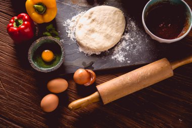 Evde pizza malzemelerle ahşap masa üzerinde hazırlanıyor