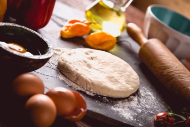 Evde pizza malzemelerle ahşap masa üzerinde hazırlanıyor