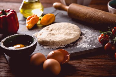 Evde pizza malzemelerle ahşap masa üzerinde hazırlanıyor