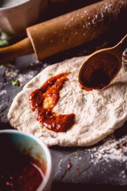 Kız taze pizza üzerine domates sosu çiziyor