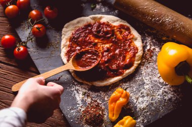 Kız taze pizza üzerine domates sosu çiziyor