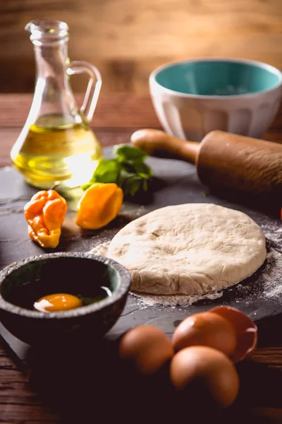 Préparation de pizza maison sur une table en bois avec des ingrédients — Photo