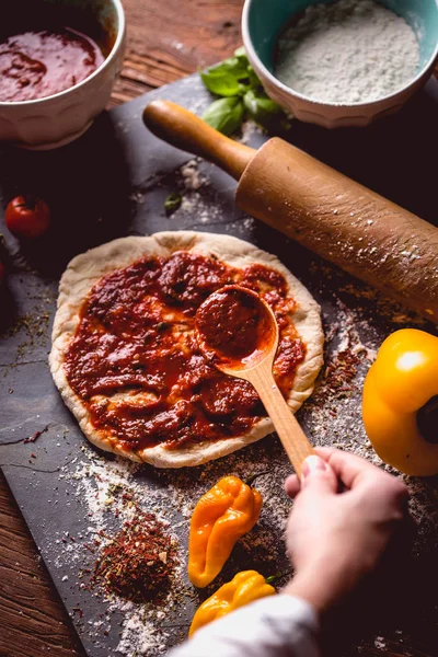 Kız taze pizza üzerine domates sosu çiziyor