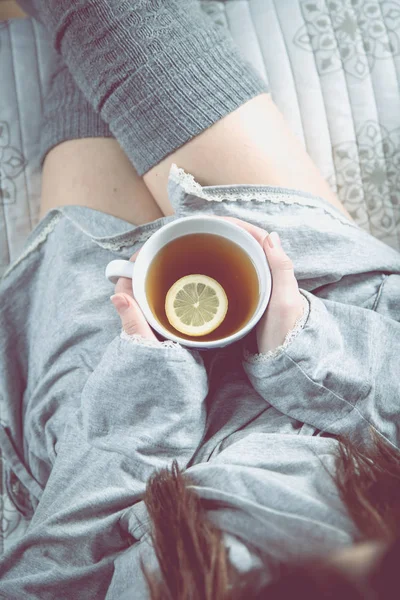 Ragazza sta bevendo tè caldo sul divano, accogliente concetto invernale — Foto Stock