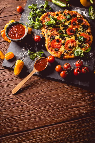 Pizza maison fraîche et savoureuse sur table en bois avec ingrédients — Photo