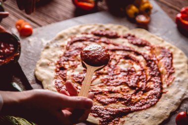 Kız taze pizza üzerine domates sosu çiziyor