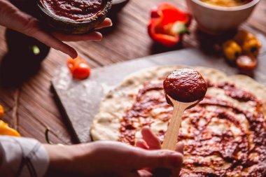 Kız taze pizza üzerine domates sosu çiziyor