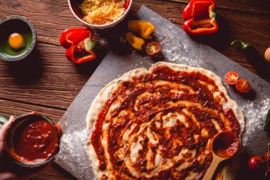 Kız taze pizza üzerine domates sosu çiziyor