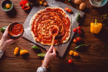 Kız taze pizza üzerine domates sosu çiziyor