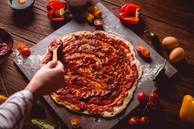 Kız taze pizza üzerine domates sosu çiziyor