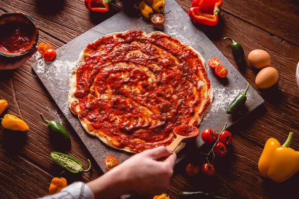 Fille place la sauce tomate sur la pizza fraîche — Photo