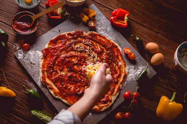 Kız taze pizza üzerine domates sosu çiziyor