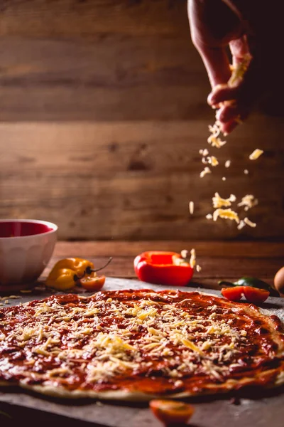 Ragazza sta diffondendo formaggio su gustosa pizza fatta in casa — Foto Stock