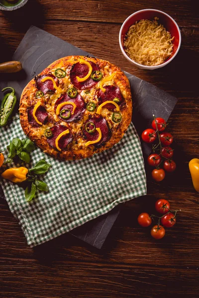 Pizza maison fraîche et savoureuse sur table en bois avec ingrédients — Photo