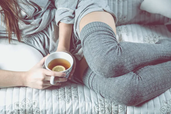 Νεαρό κορίτσι πίνει τσάι στον καναπέ, άνετο έννοια — Φωτογραφία Αρχείου