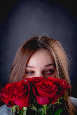 Güzel kız bir buket kırmızı gül, koyu arka plan düzenliyor
