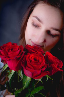 Güzel kız bir buket kırmızı gül, koyu arka plan düzenliyor