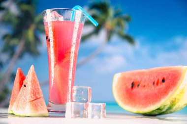 Karpuz buz soğuk içecek avuç içi ile bir plajda