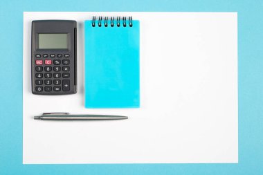 Çalışma alanı üst görünümü. Ofis masası, ofis malzemeleri ve hesap makinesi. Üst görünüm mavi arkaplan