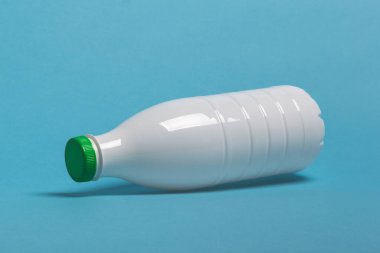 süt ürünleri için beyaz plastik şişe mavi arka planda yatıyor