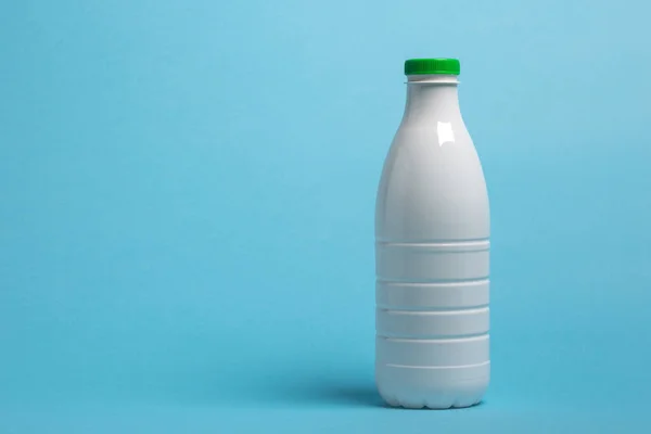 Süt ürünleri için beyaz plastik şişe mavi arka planda duruyor
