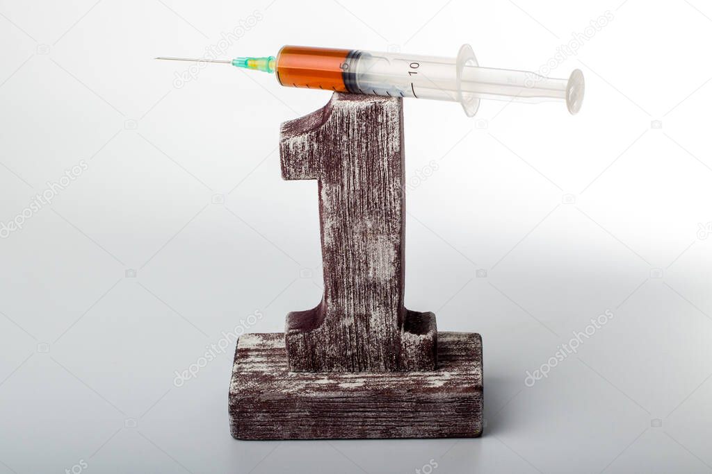 syringe with red liquid lies on a wooden figure one