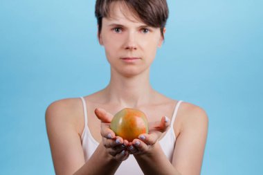 Elinde kırmızı bir elma olan beyaz bir kadının yakın çekimleri var. Sağlıklı beslenme fikrinin iyi bir sağlık temeli olduğu fikri.