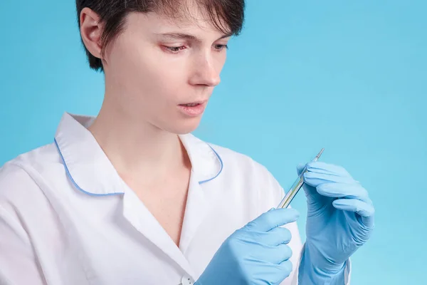 Portrait Young Woman Doctor Blue Background Who Looks Thermometer Worries — Stock Photo, Image