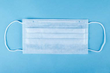 Mavi arka planda tıbbi bir maskenin yakın çekimi. Koronavirüsten koruma