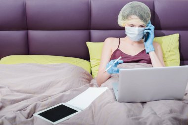 Covid-19 Coronavirus 'la evde çalış. Koruyucu eldivenli bir kız, maske ve saçında bir şapka. Yeni gerçeklik.