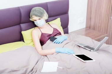Covid-19 Coronavirus 'la evde çalış. Koruyucu eldivenli bir kız, maske ve saçında bir şapka. Yeni gerçeklik.