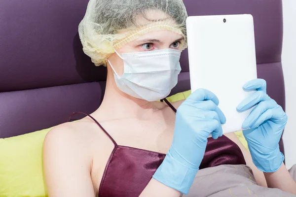 Kendini izole et ve evde covid-19 koronavirüsle çalış. Koruyucu eldivenli bir kız, maske ve saçında bir şapka. Yeni gerçeklik. Normal yaşam ve izole çalışma