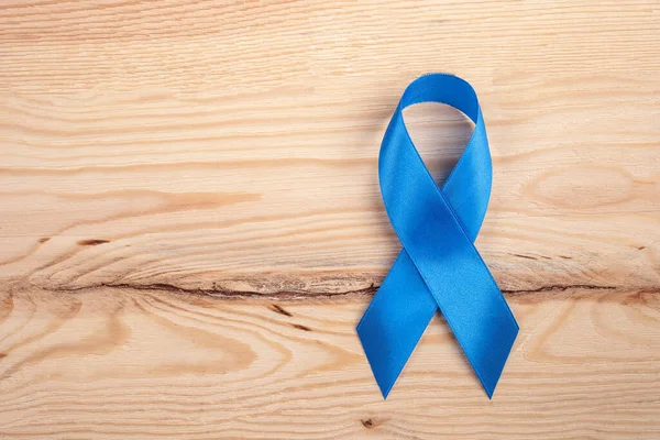 Blue ribbon as a symbol of prostate cancer awareness. blue ribbon on a wooden background. close up