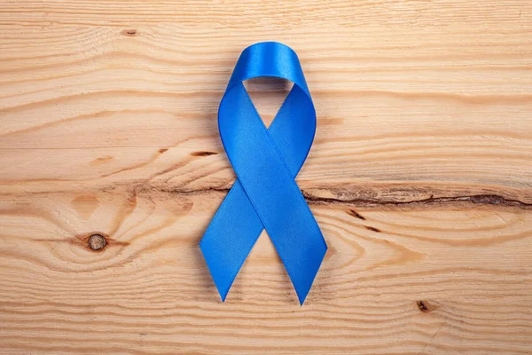 Blue ribbon as a symbol of prostate cancer awareness. blue ribbon on a wooden background. close up
