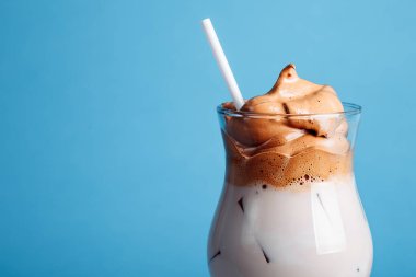 Buzlu Dalgona Kahvesi, parlak mavi arka planda yumuşacık kremalı kremalı kremalı kahve. kahvede yeni trendler