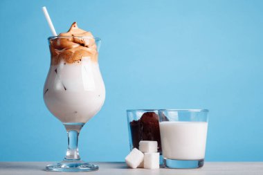 Buzlu Dalgona Kahvesi, parlak mavi arka planda yumuşacık kremalı kremalı kremalı kahve. kahvede yeni trendler
