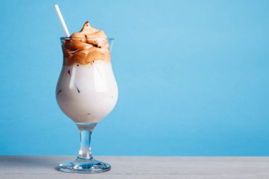 Buzlu Dalgona Kahvesi, parlak mavi arka planda yumuşacık kremalı kremalı kremalı kahve. Soğuk kahvede yeni trendler