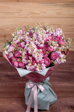 Güllü güzel bir buket çiçek ve ahşap arka planda pembe pakette Mattioli. yüksek kalite.