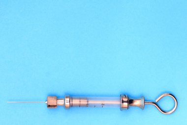 Mavi arka planda metal ve camdan yapılmış antika şırınga. Metin için boş alan. kopyalama alanı