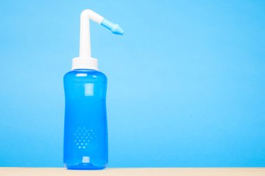 Mavi arkaplanda mavi su darbesi burun yıkama şişesi, burun sulama kavramı