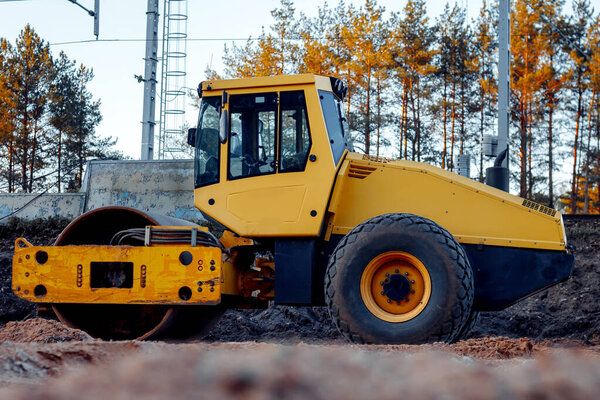Тяжелый вибрационный каток без водителя на песчаной дороге в качестве примера отдыха между дорожными работами.
